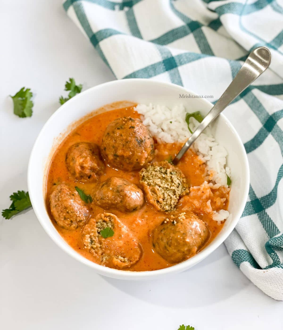 A bowl is with falafel curry and rice on the table.