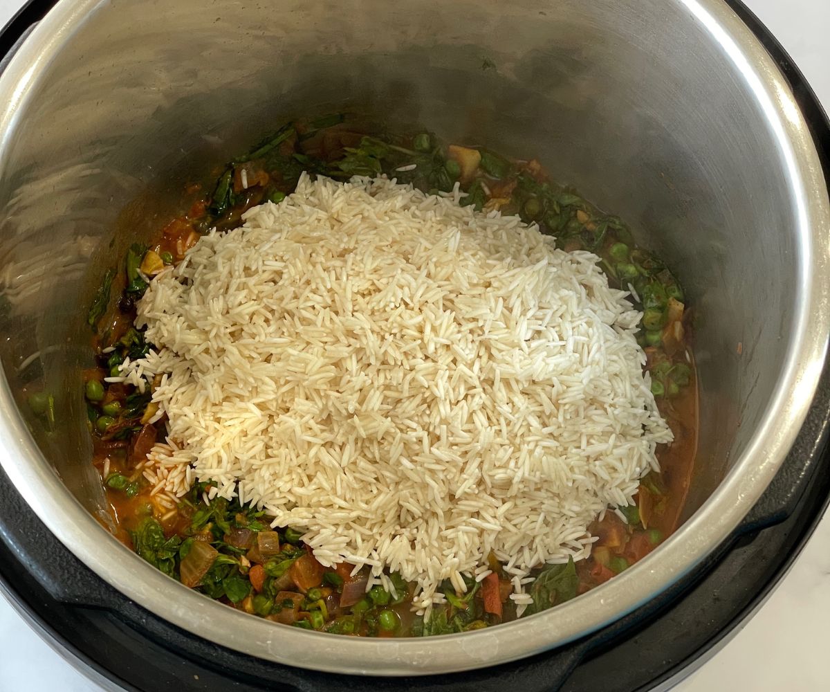 An instant pot is with uncooked methi rice mixture.