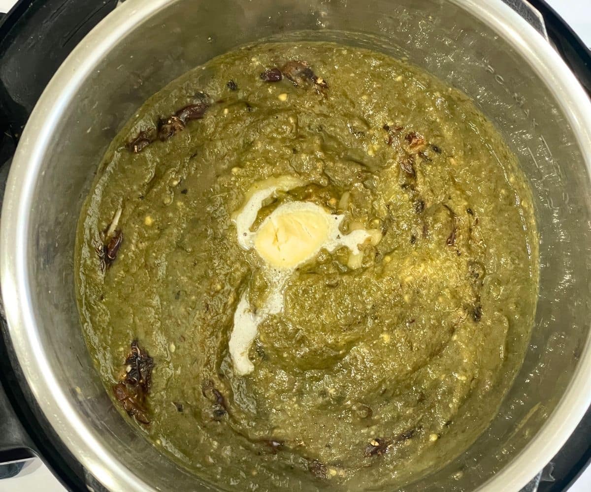An instant pot is with sarson ka saag curry topped with vegan butter.