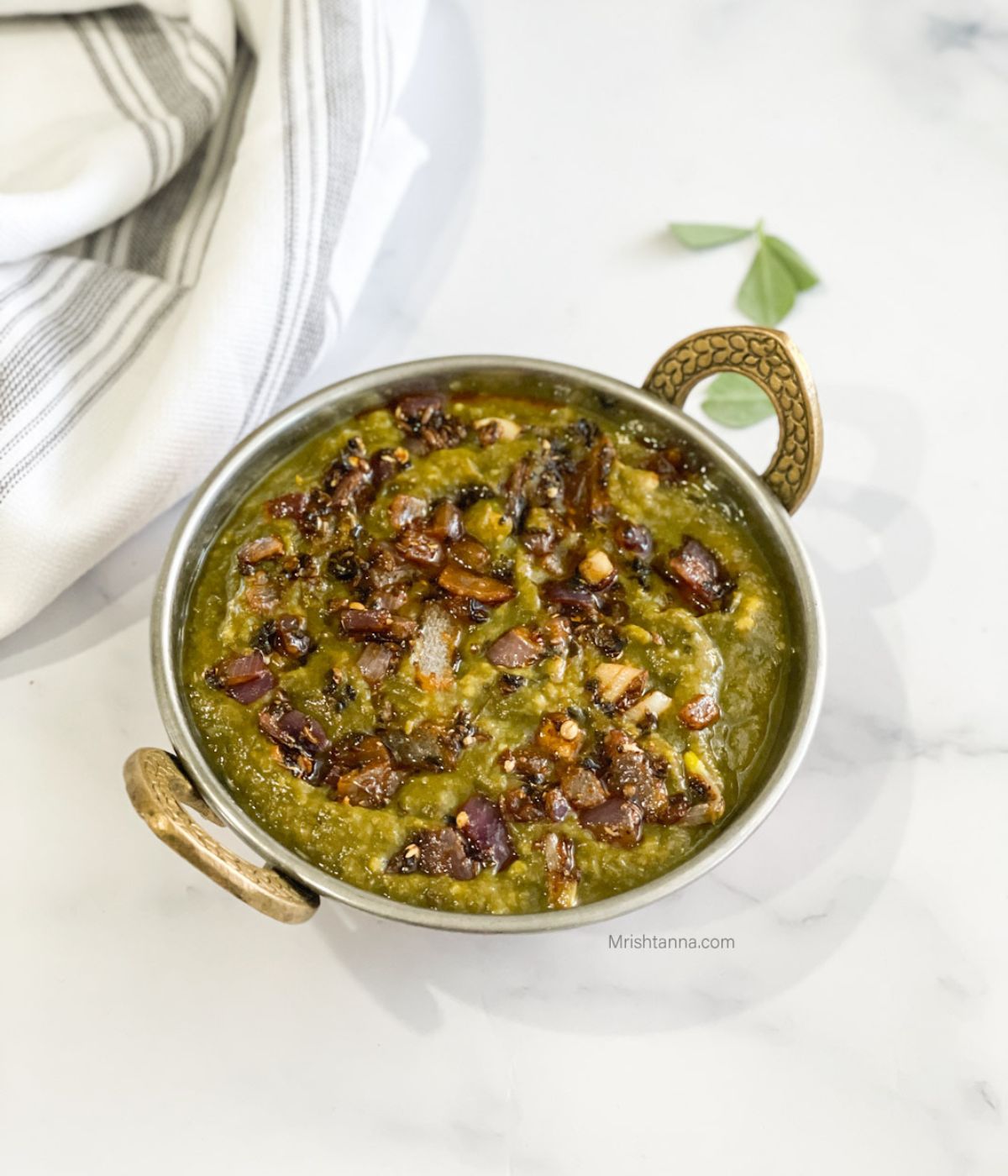 A copper bowl is with sarson ka saag curry.