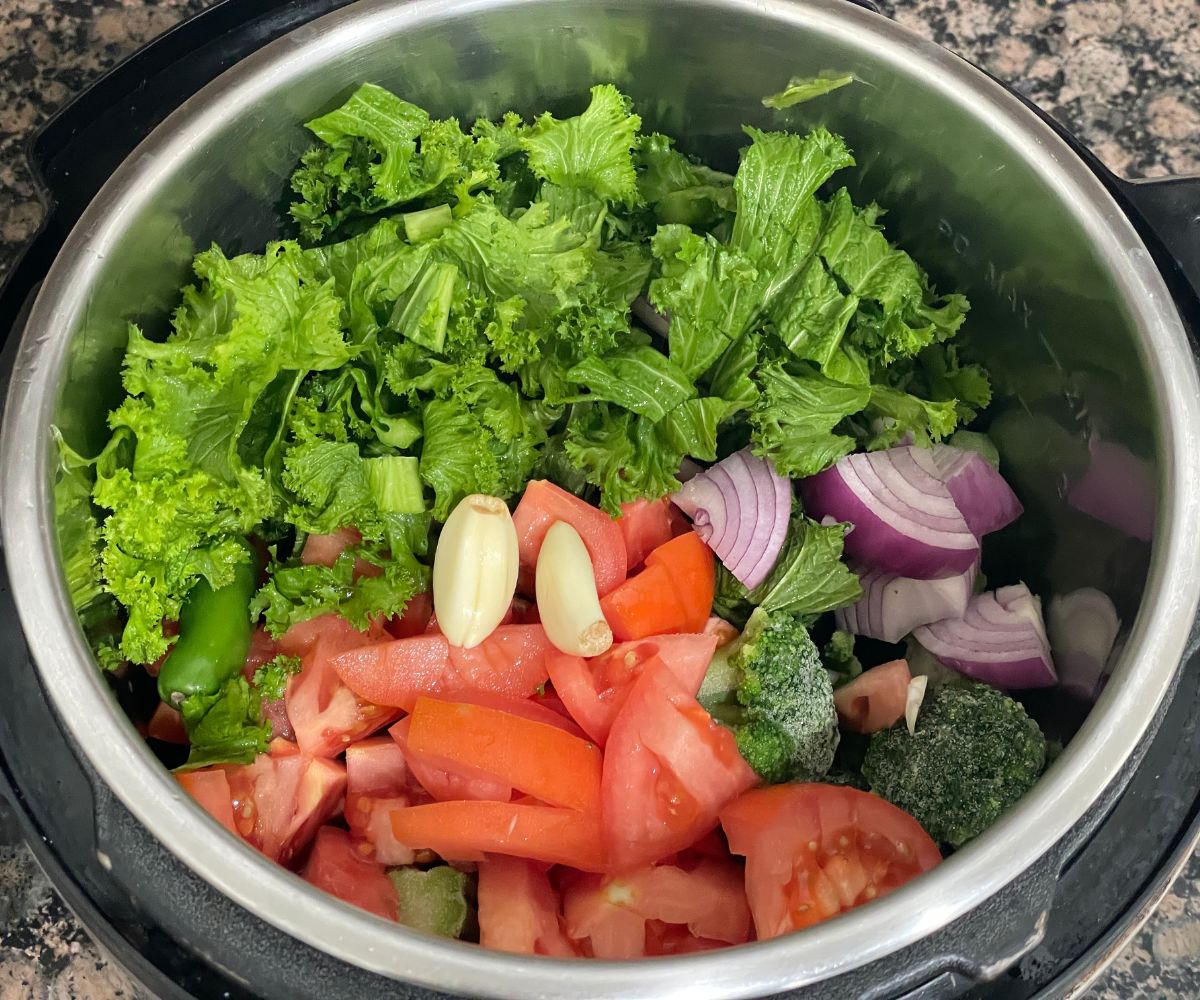 An insatnt pot is with greens, and all the ingredients for saag curry.