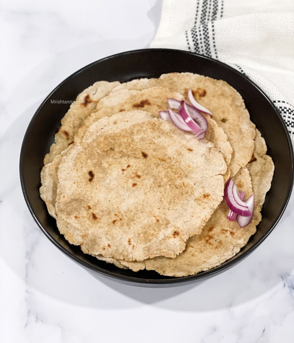 A plate is with jowar roti's on the table.