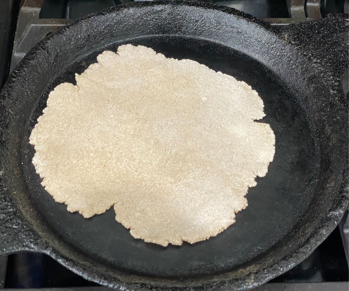 A tawa is with sorghum roti over the heat.