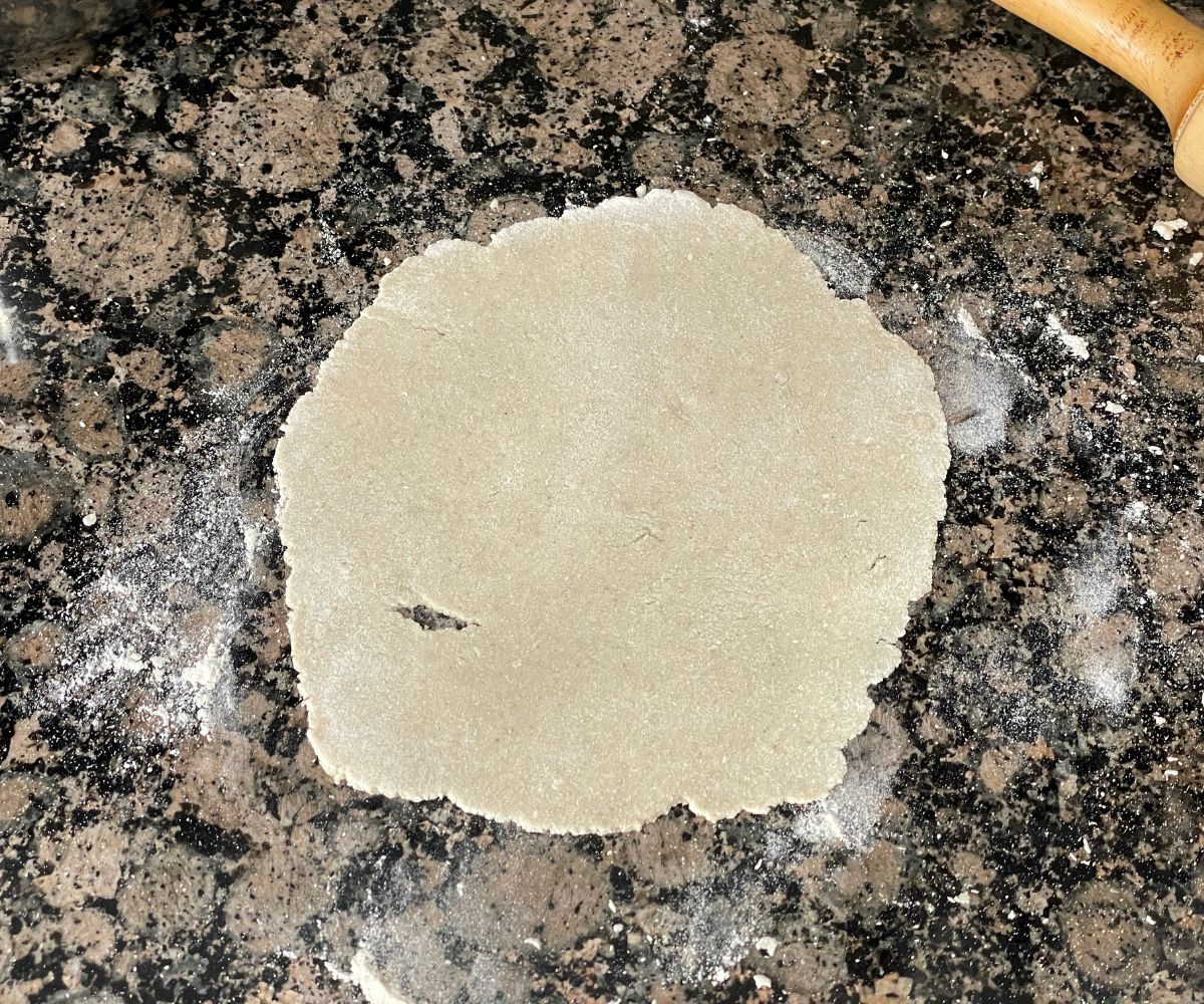 Flattened sorghum roti dough is on the surface. 
