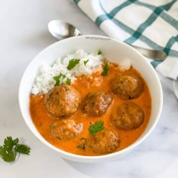 A bowl of falafel curry and rice on the table.