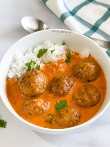 A bowl of falafel curry and rice on the table.