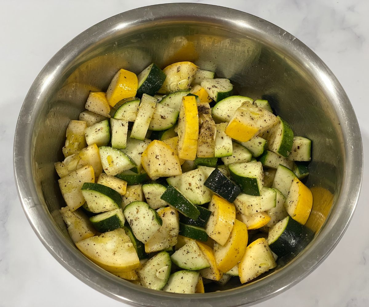 A bowl is with cubed zucchini and seasonings.