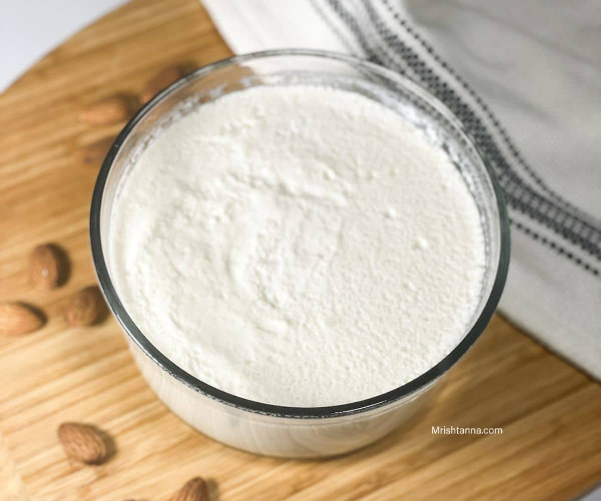 A bowl of almond milk yogurt is on the wooden tray.