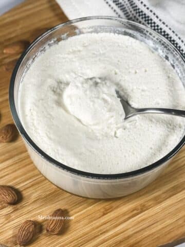 A spoon of almond milk yogurt is placed on the bowl.