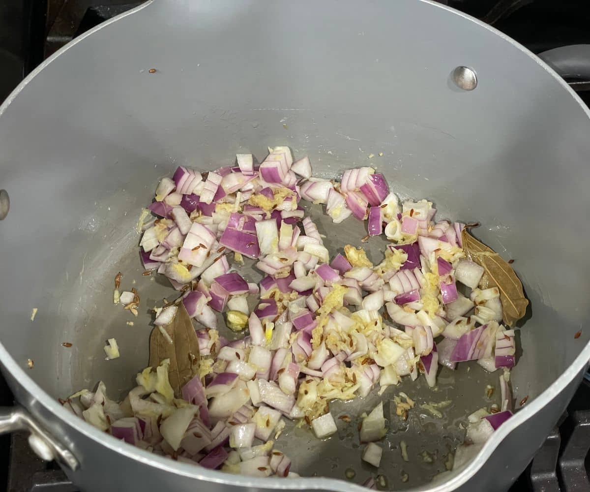 A pan is with chopped onions and garlic over the heat.