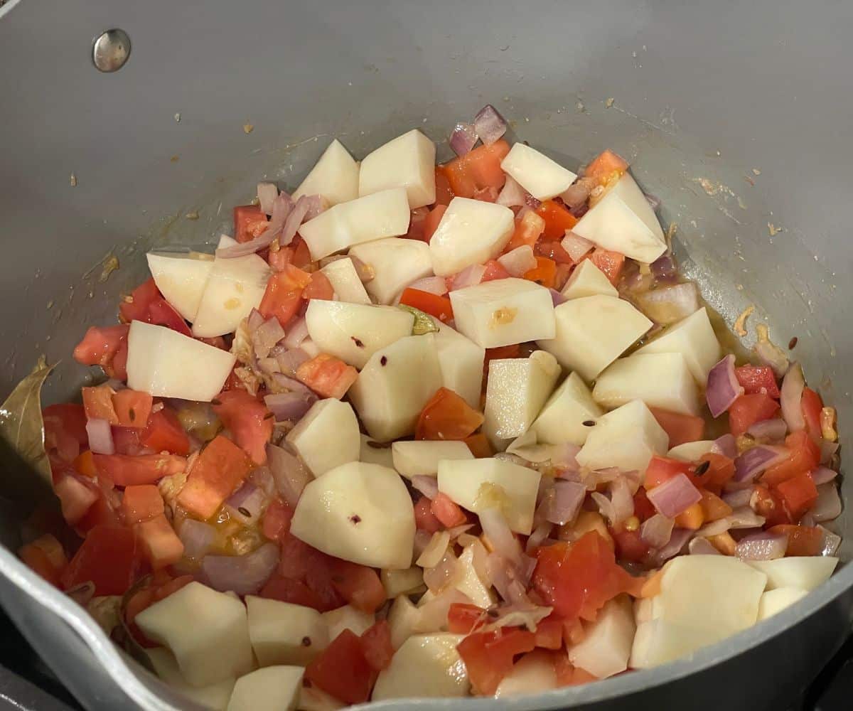 A pan is with potatoes and spices over the flame.