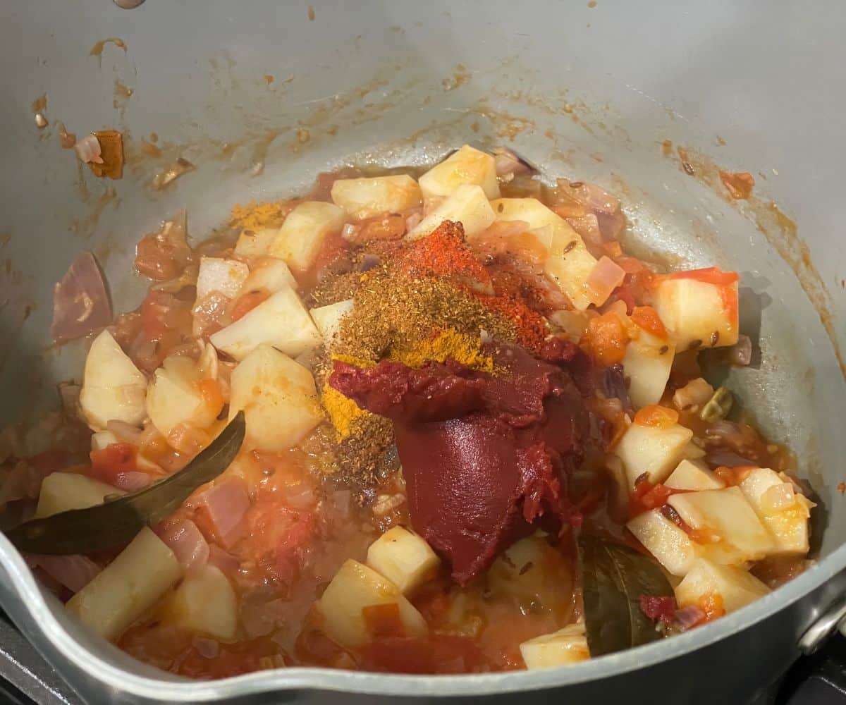 A pan is with spices and masalas for aloo chana curry.