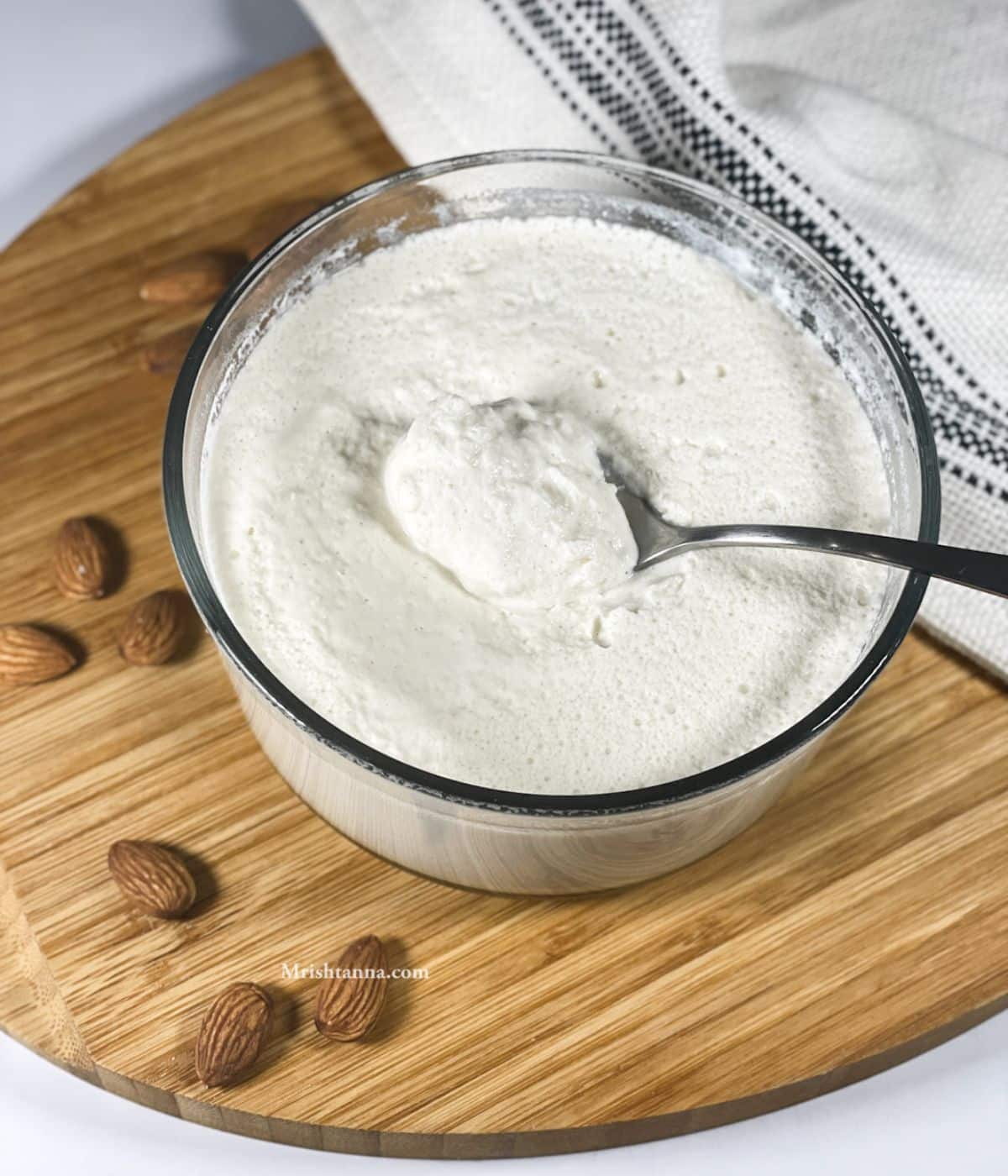 A glass bowl of almond milk yogurt is on the tray with a spoon. 