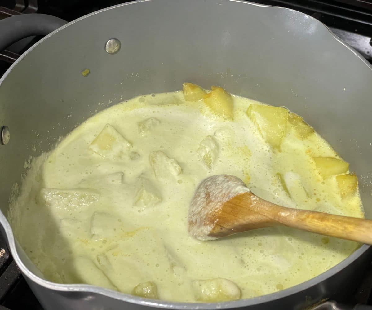 A pot is with ash gourd cubes and majjige huli masala over the heat.