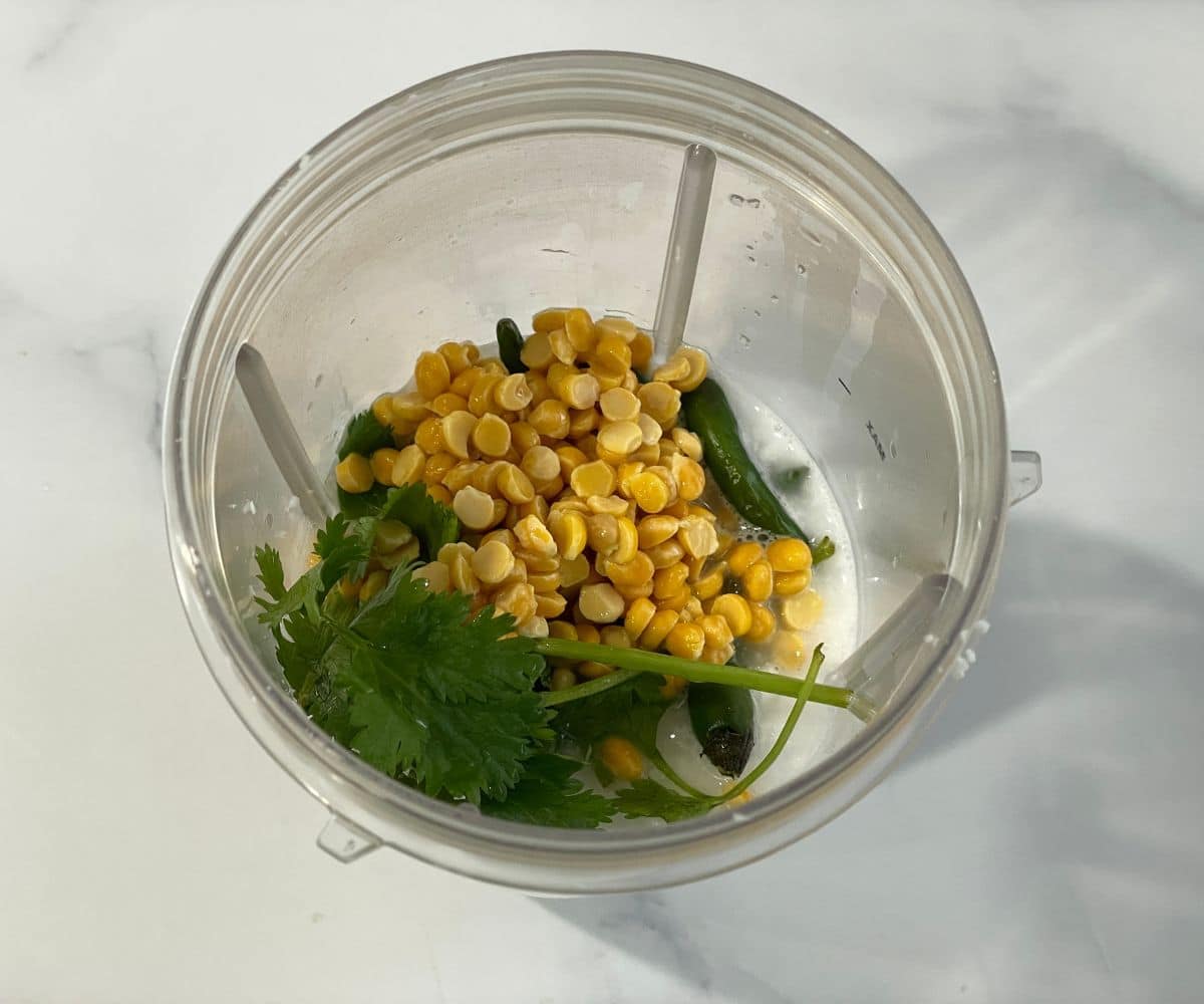 A blender is with grated coconuts and soaked chana dal for majjige huli.