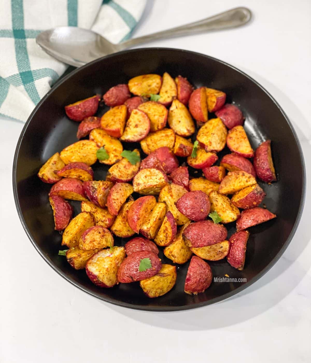 A black plate is with air fryer radishes.