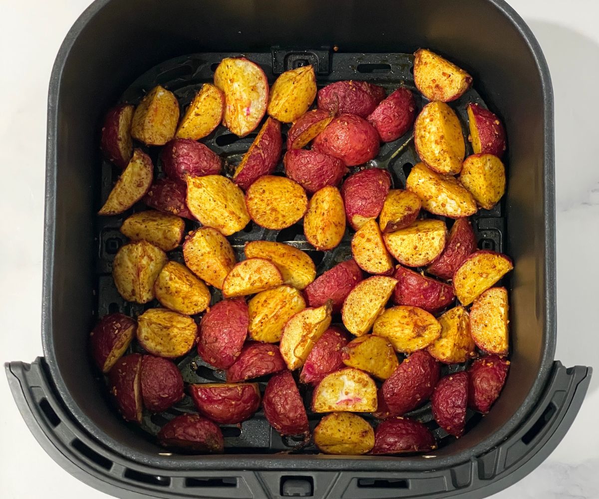 The air fryer basket is with roasted radishes.