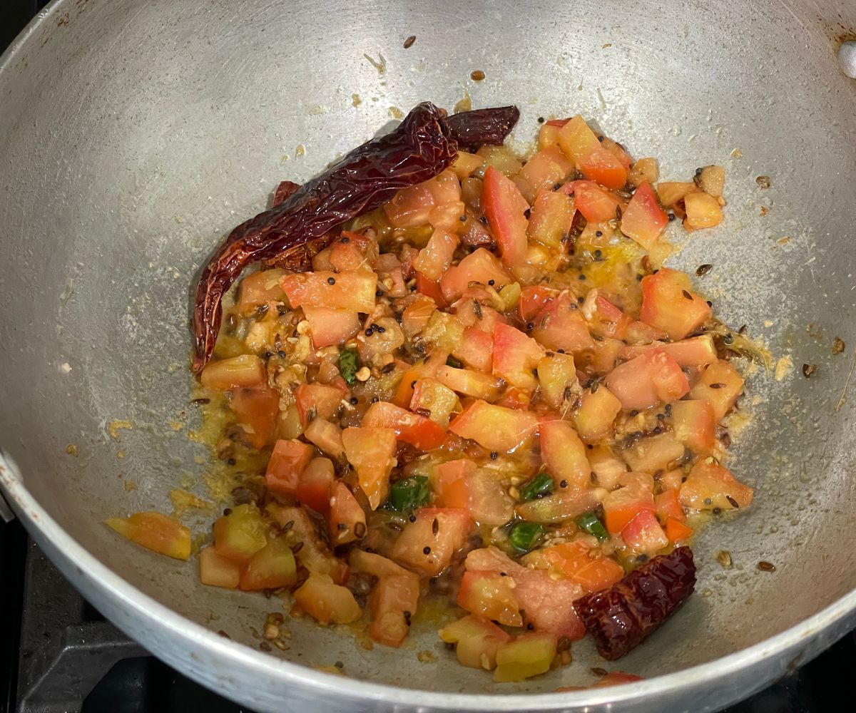 A pot of spices and tomatoes over the heat.