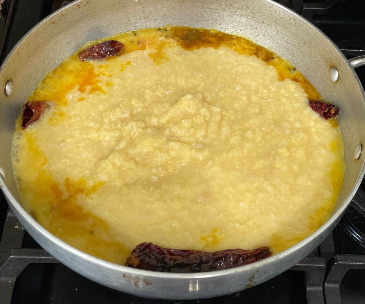 A pot is with spices and moong dal over the heat.