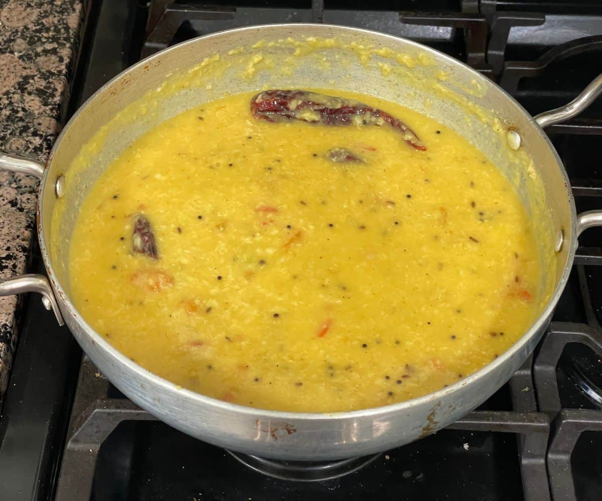 A pot is with Bengali Moong dal over the stove top.