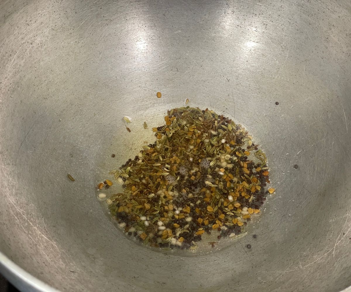 A pot is with oil and whole spices over the heat.