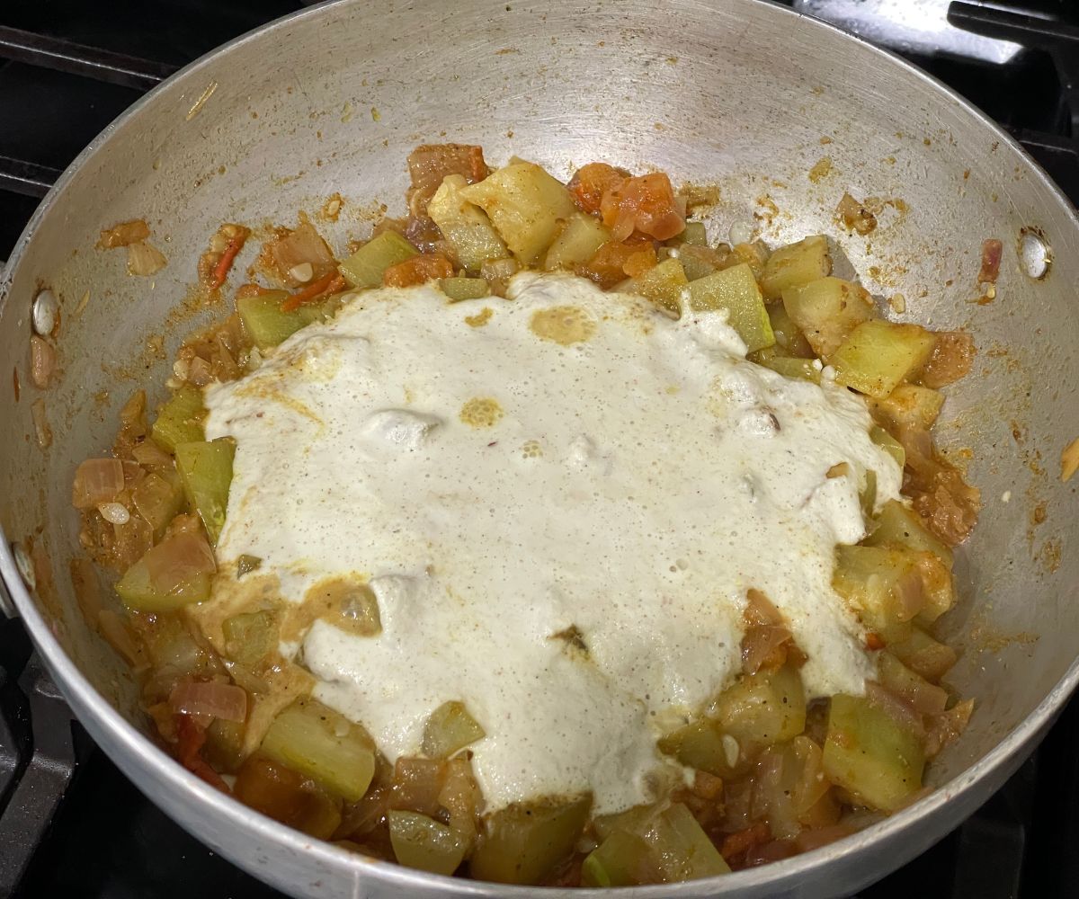 A pan is with bottle gourd and kurma paste over the heat.