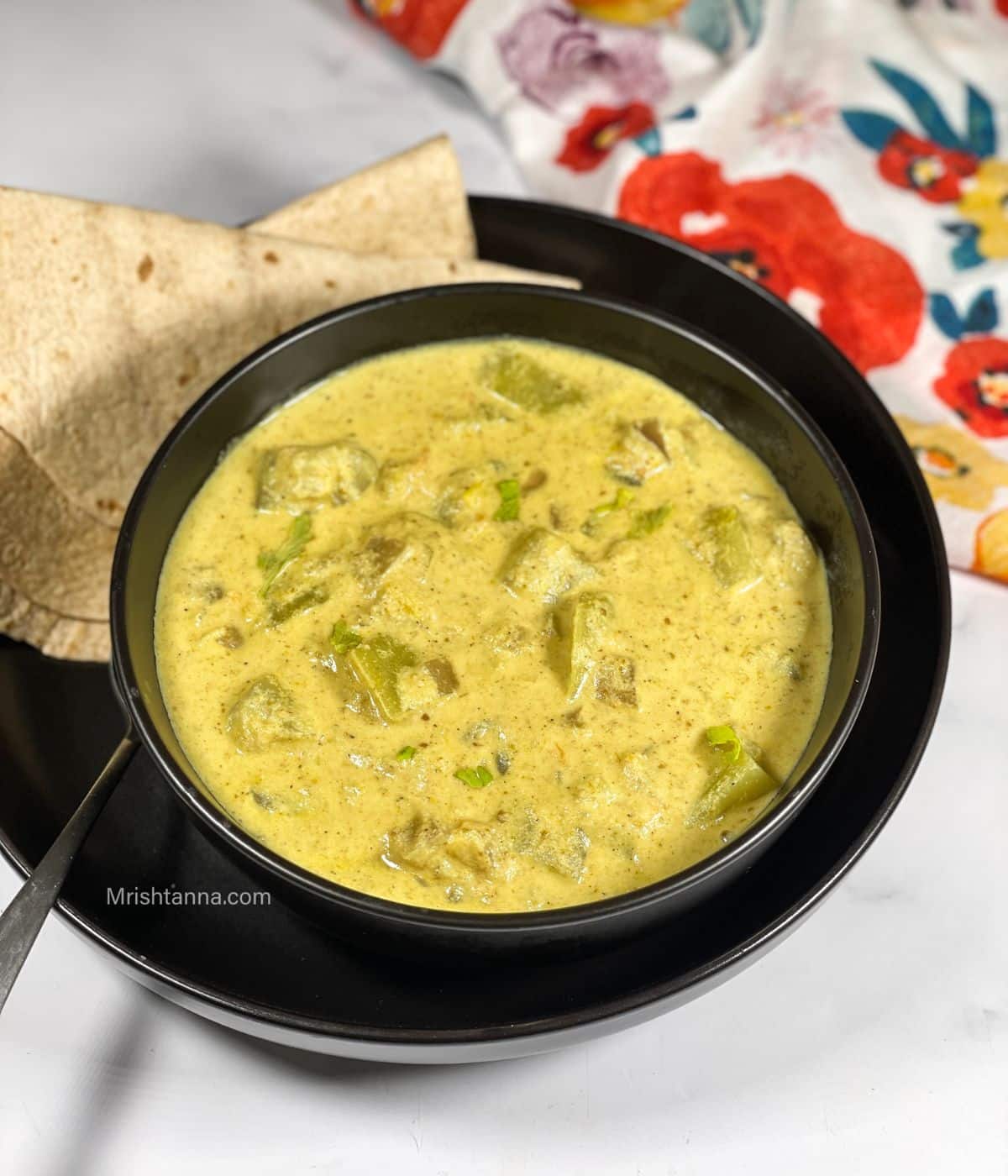 A bowl is with sorakkai kurma on the plate with chapati's.