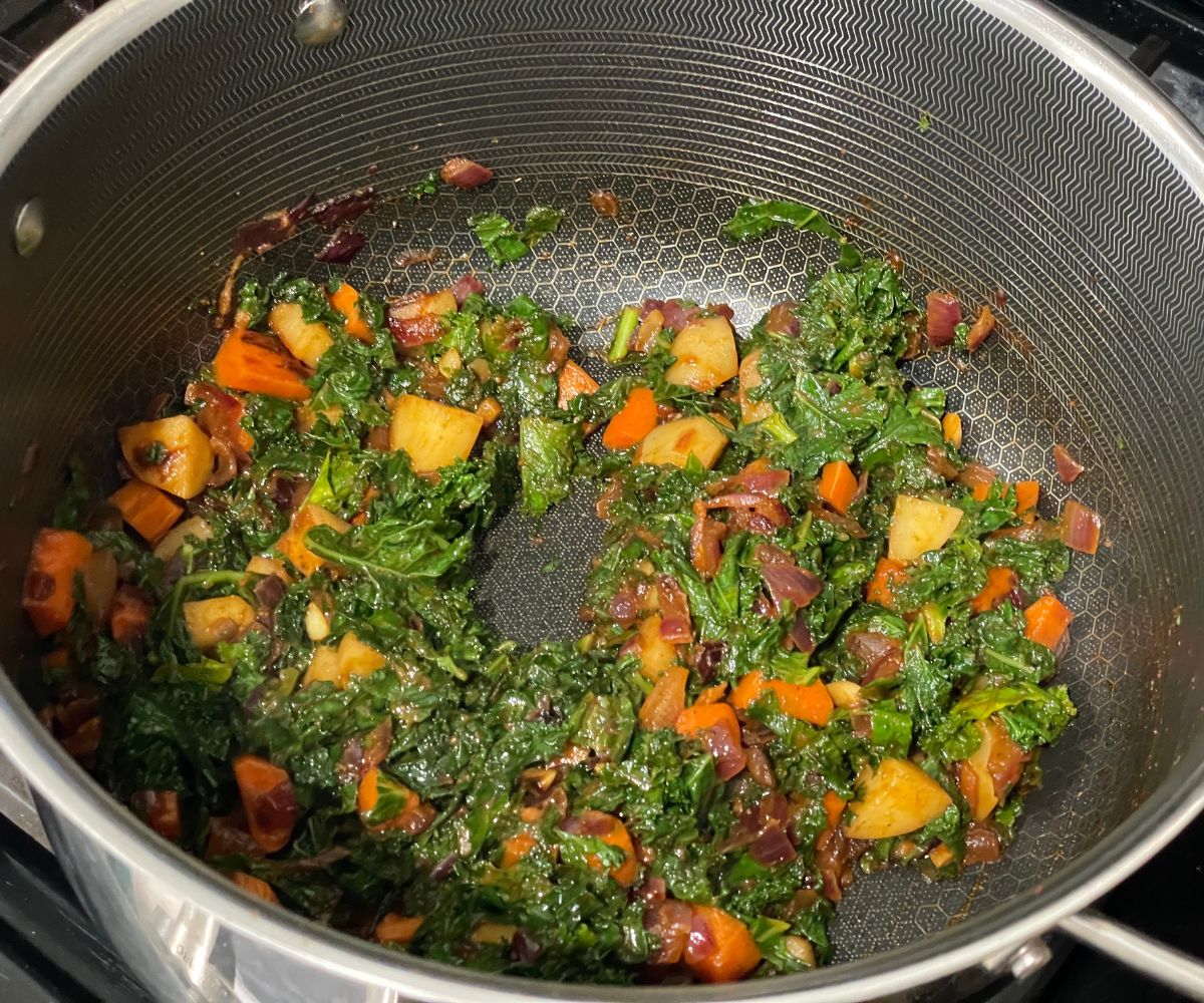 A hot pot is with sauteed veggies and kale.