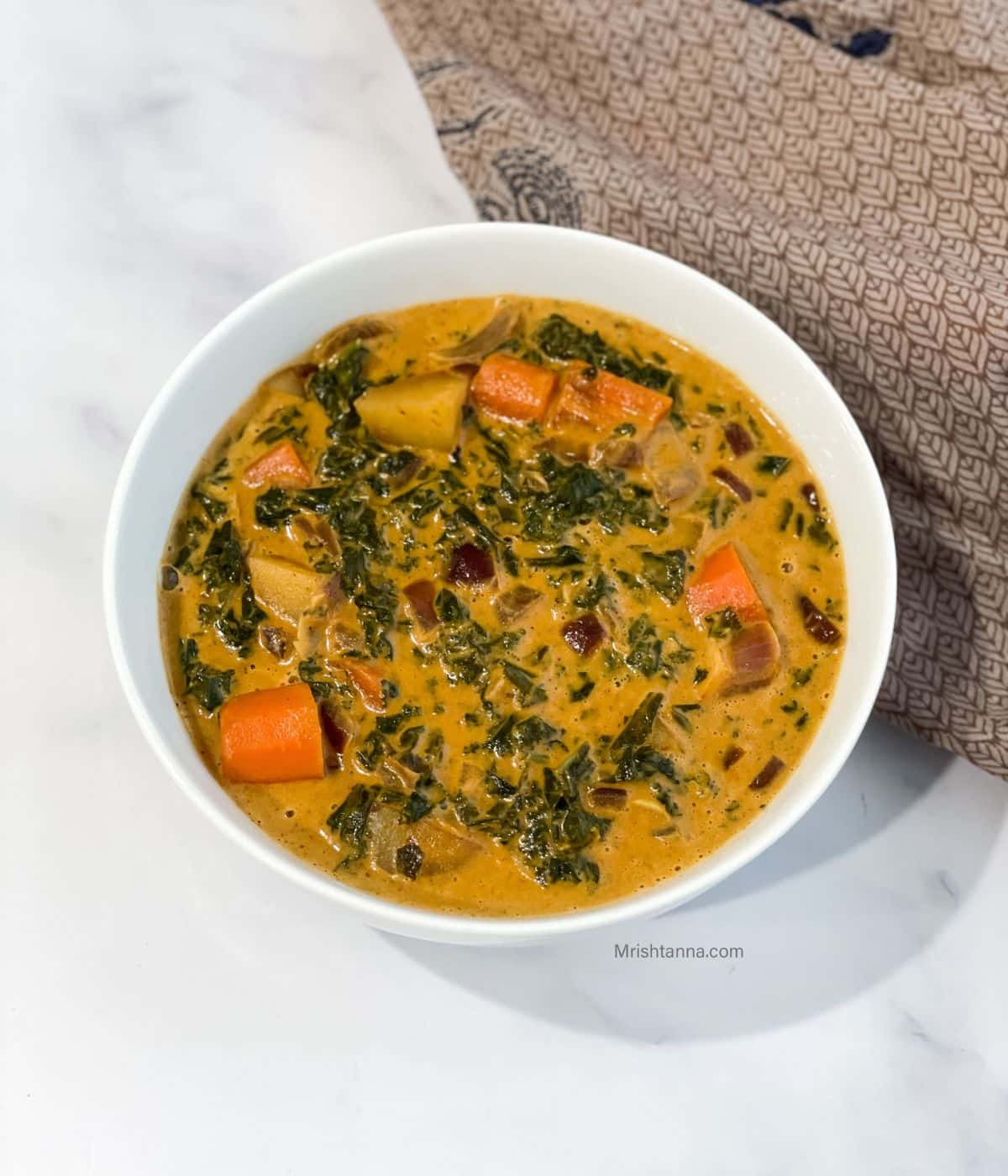 A bowl of kale curry is on the table.