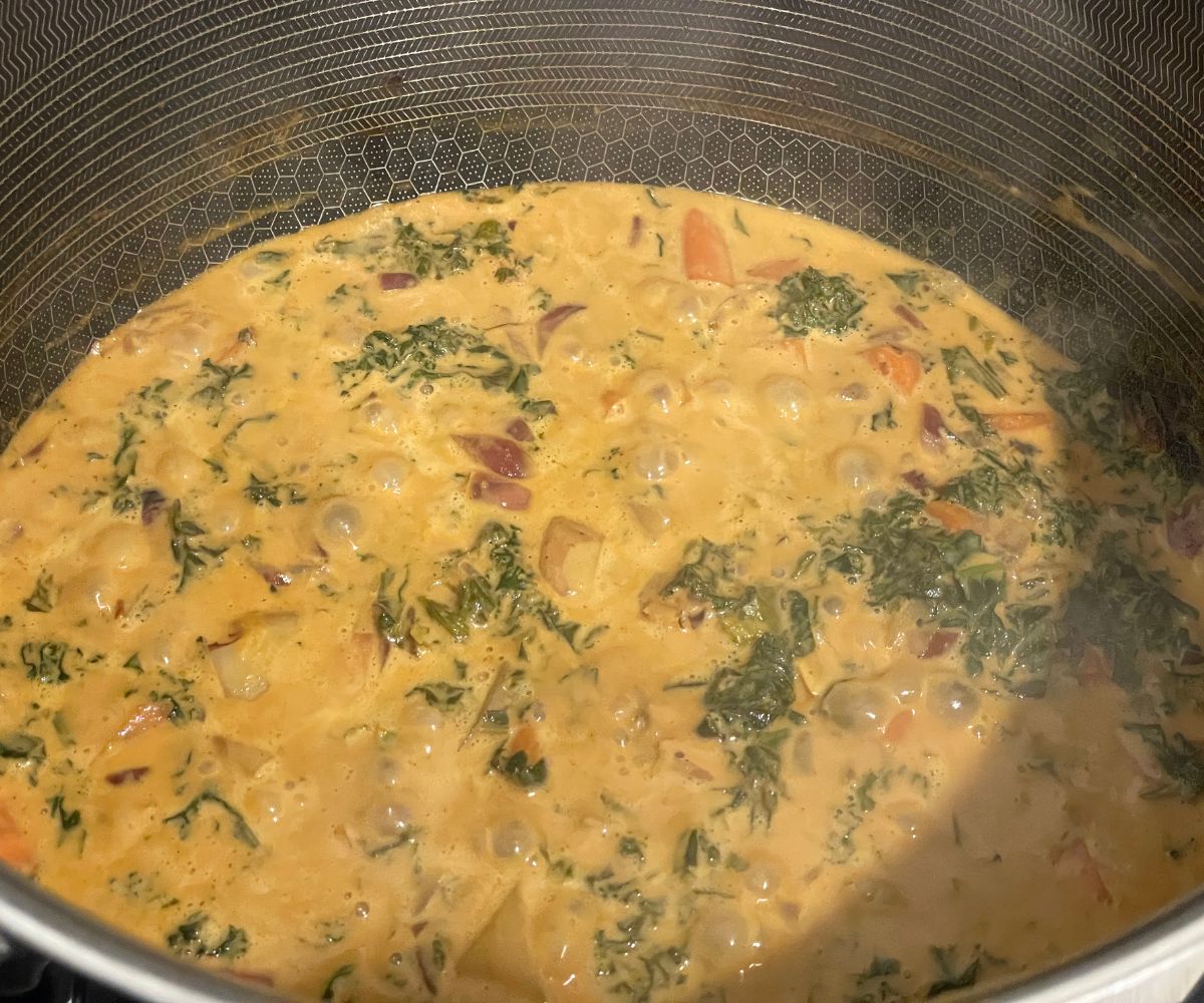 A pot of kale curry is on the heat.