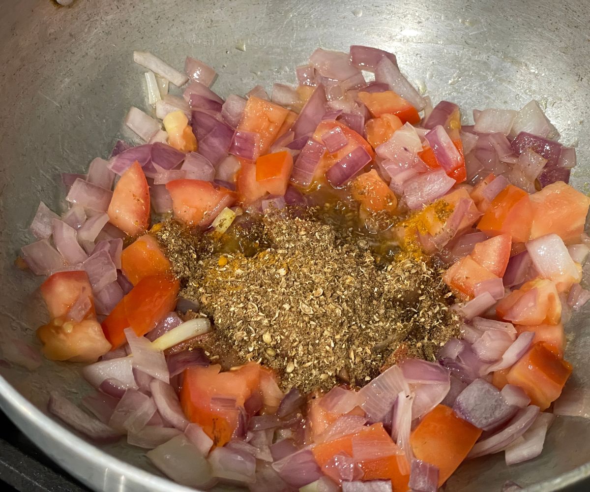 A pot is with spices and tomatoes over the heat.