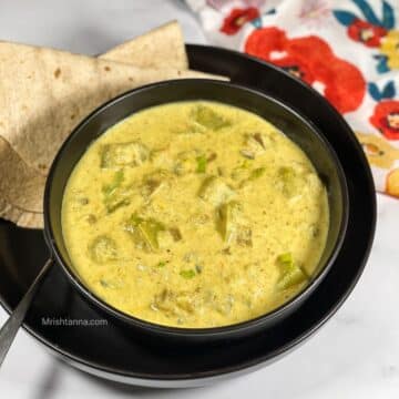 A bowl of bottle gourd kurma is on the table with rotis.