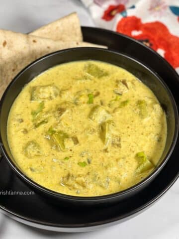 A bowl of bottle gourd kurma is on the table with rotis.