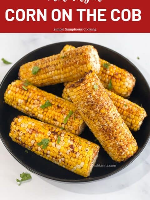 A plate of air fried corn on the cob is on the table.