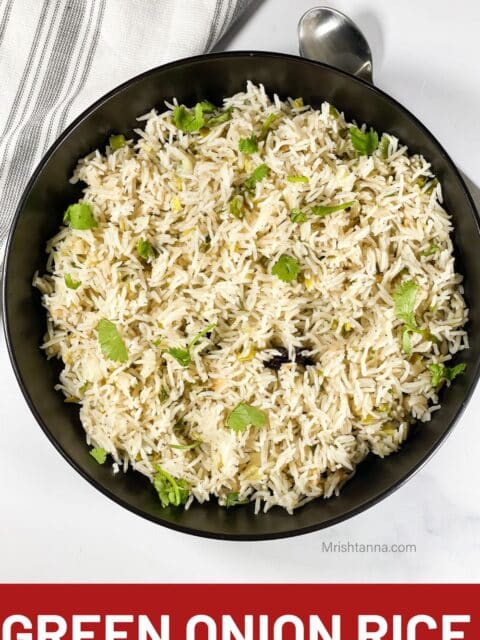 Green onion rice is served in a plate with a spoon.