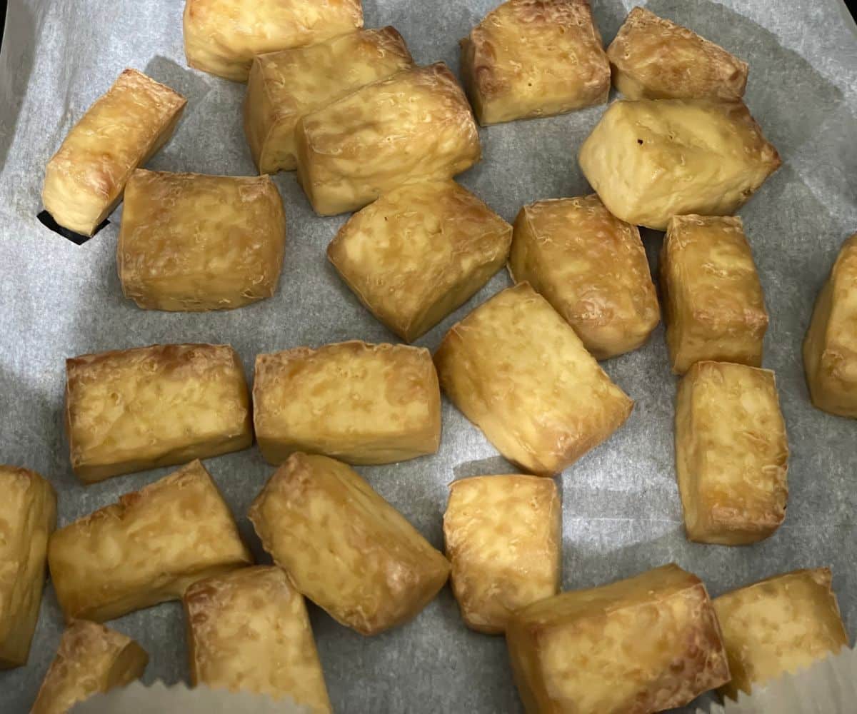 Air fryer basket is with air fried tofu cubes.