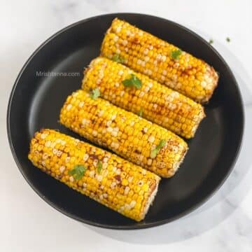 Corn on the cob is topped with spices.