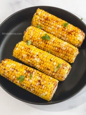 Corn on the cob is topped with spices.