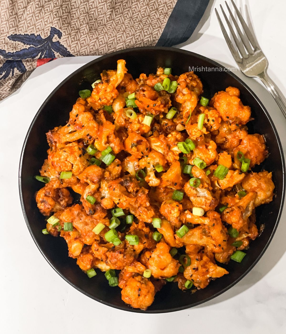 A plate of air fried lasuni gobi is on the table.