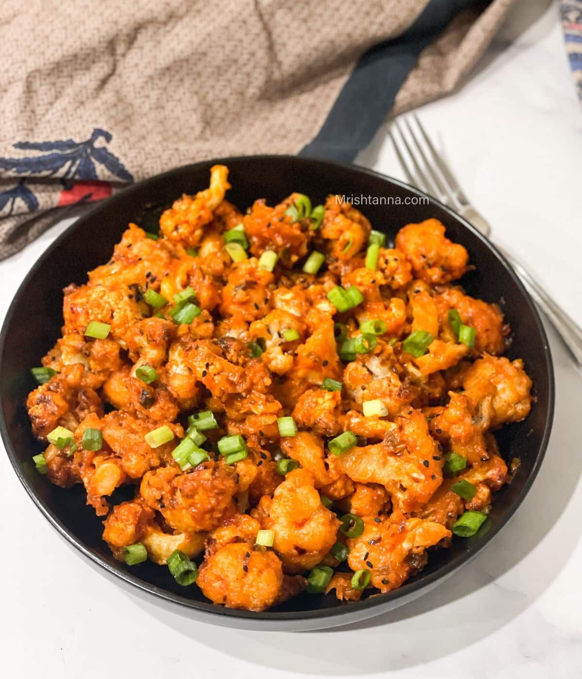 A plate if lasuni gobi is on the surface with a fork.