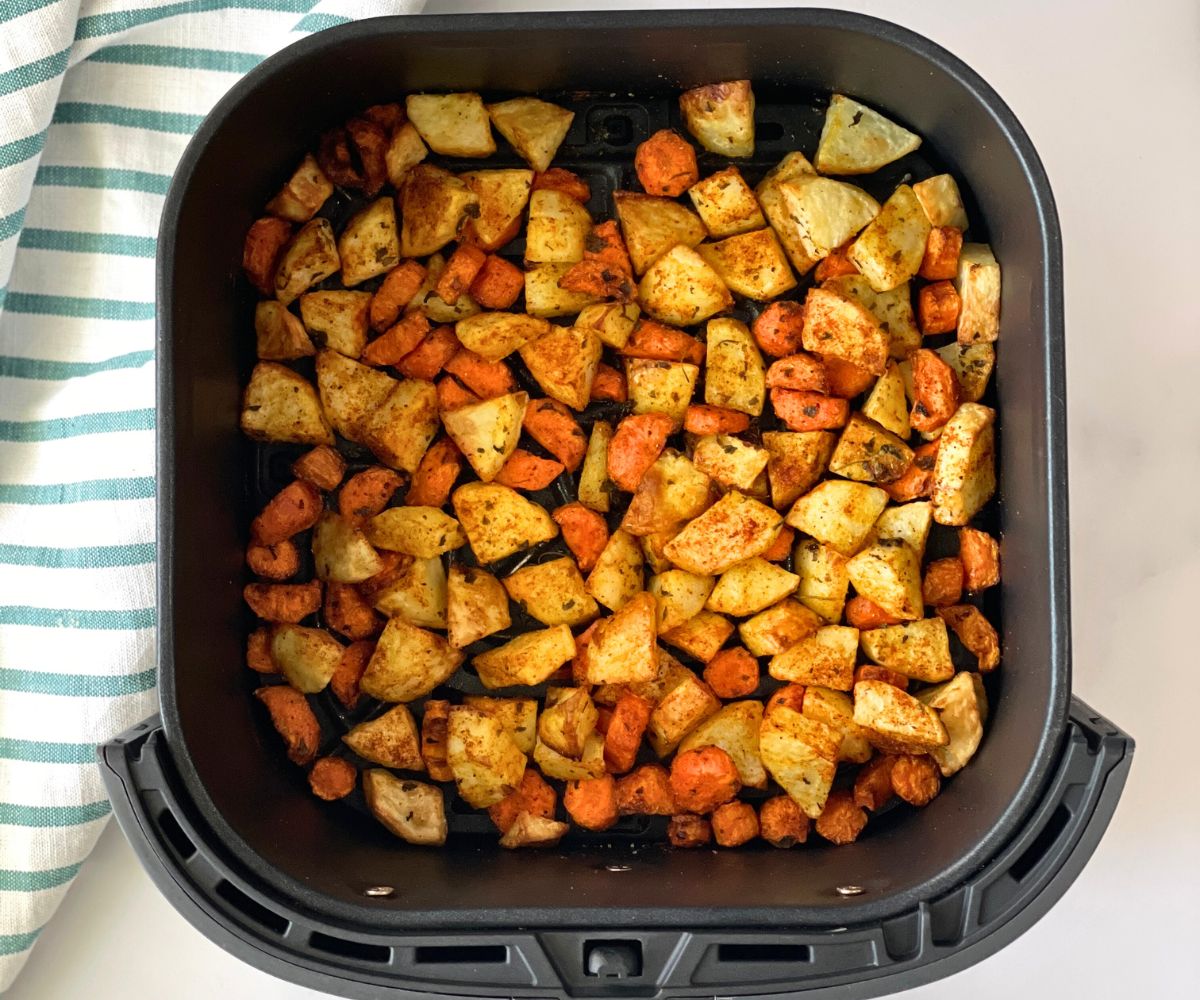 The air fryer basket is with roasted carrots and potatoes.