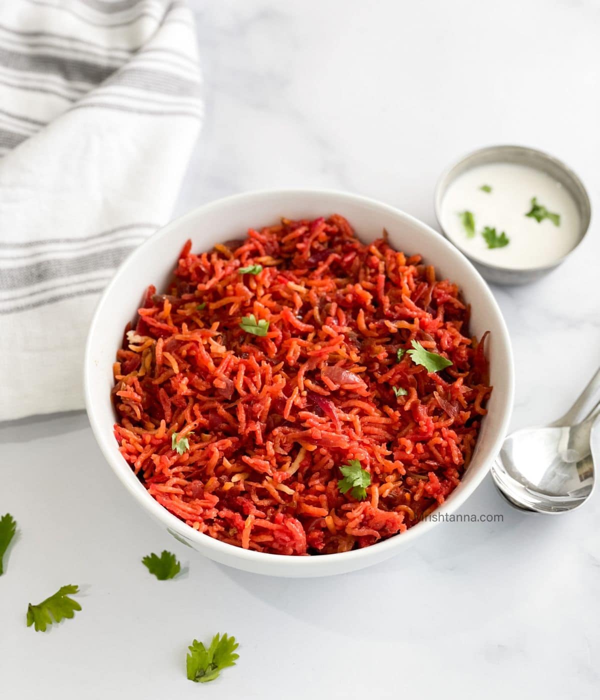 A bowl of beetroot pulao is on the table with raita.