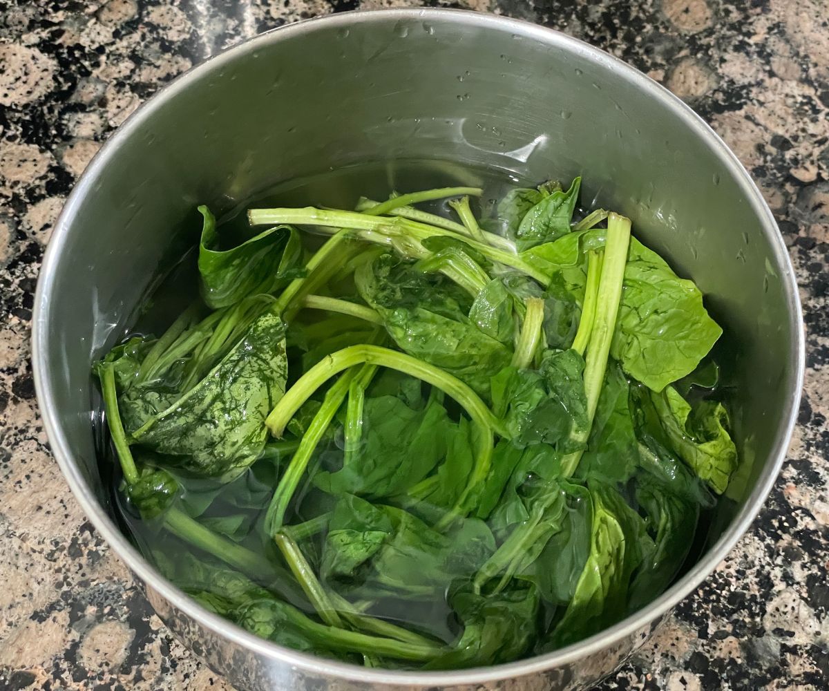 A pot is with water and spinach leaves.
