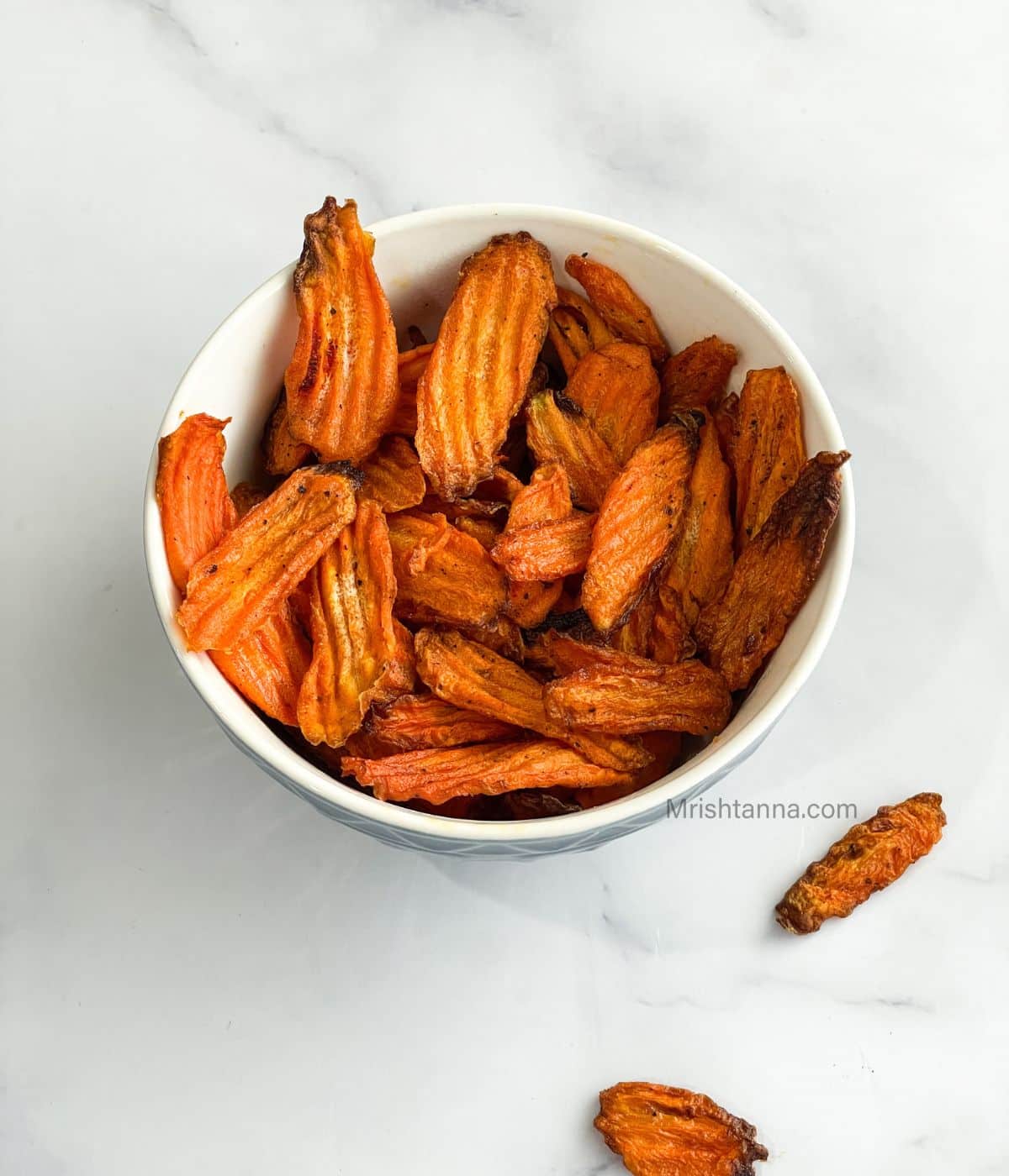 A bowl of carrot chips is on the surface.