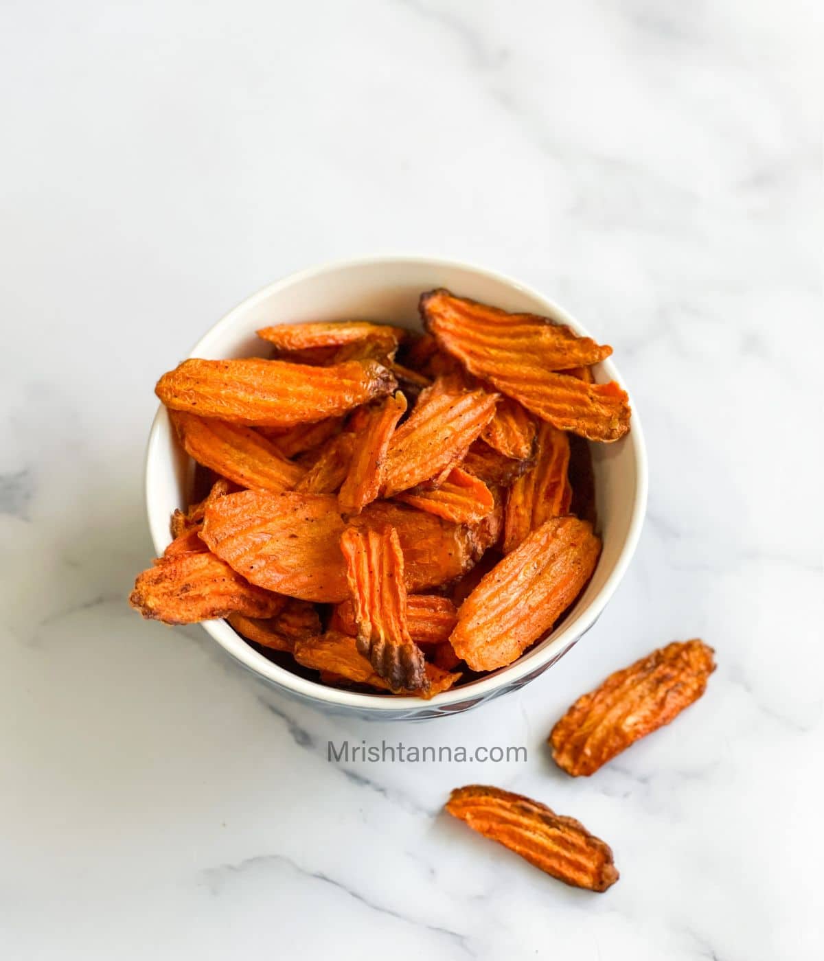 A bowl of air fryer carrot chips are on the table.