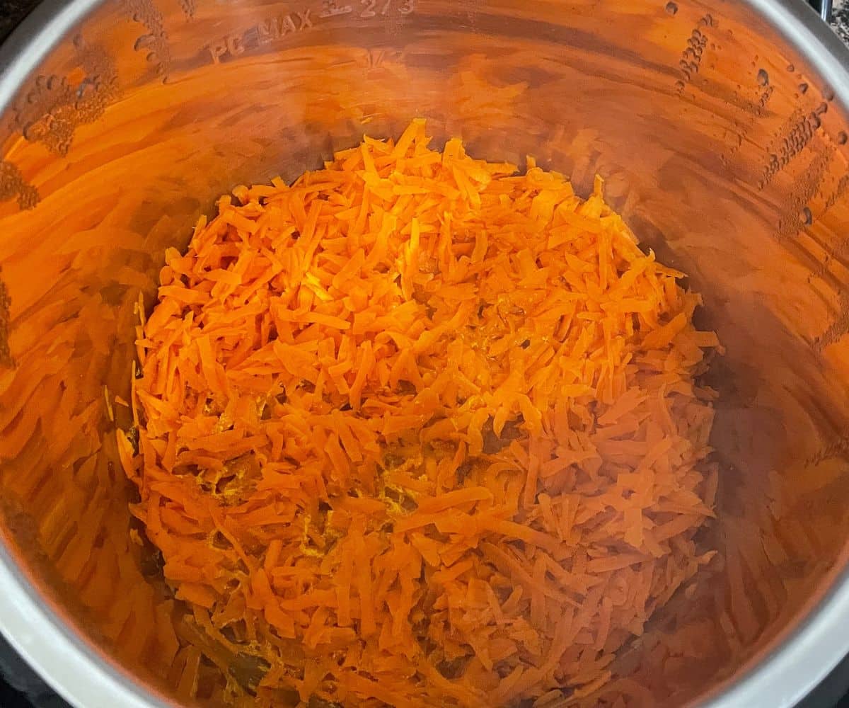 An instant pot is with cooked grated carrots.