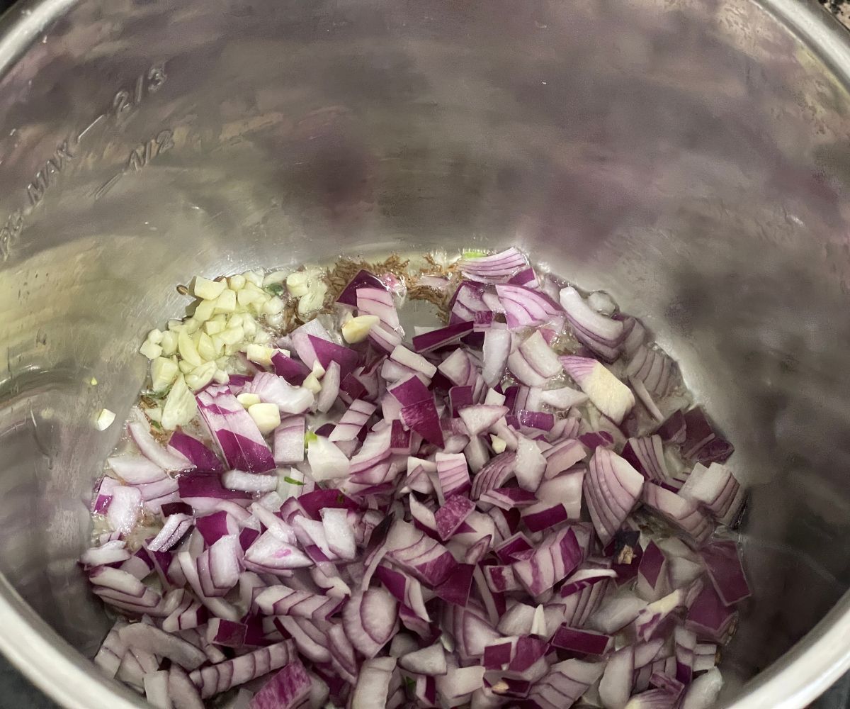 A pot is with onions, garlic on saute mode.