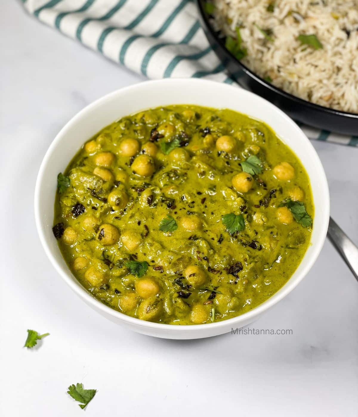 A bowl of chana palak curry is on the table.