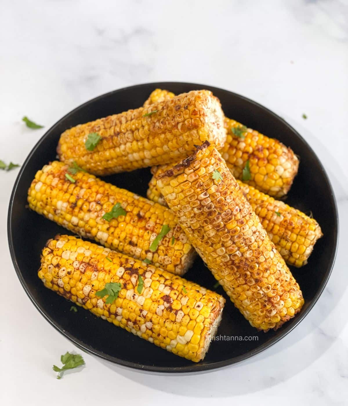A plate of air fryer corn the cob is on the table.
