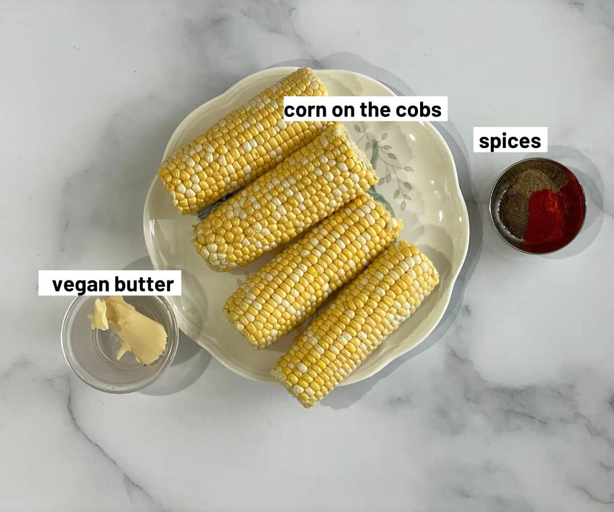 Table covered with corn on the cob, spices and vegan butter.